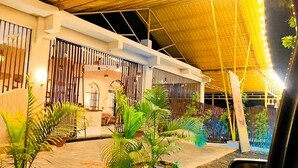 Un bâtiment moderne doté d’un patio couvert, de grandes fenêtres et de plantes tropicales.