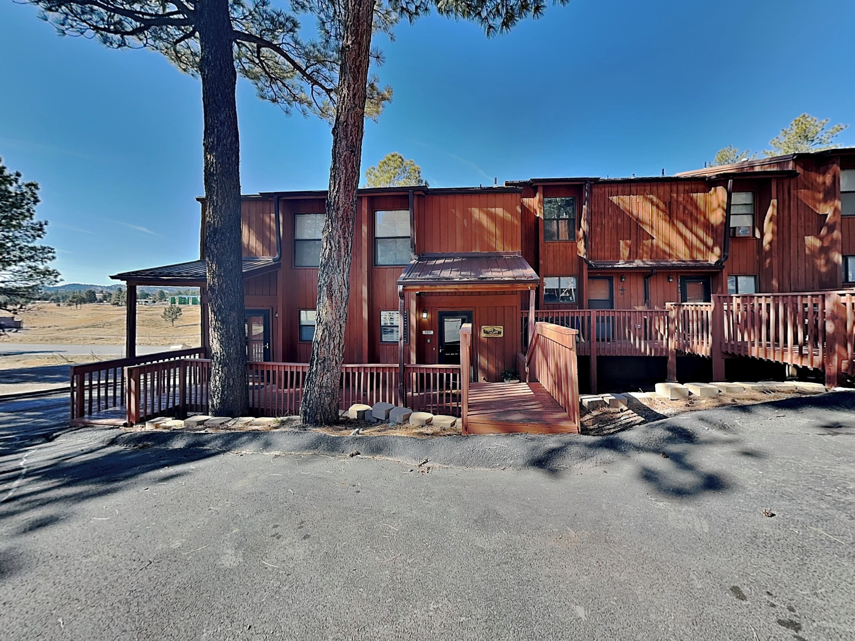A two-story wooden building with a porch and a small staircase leading to the entrance.