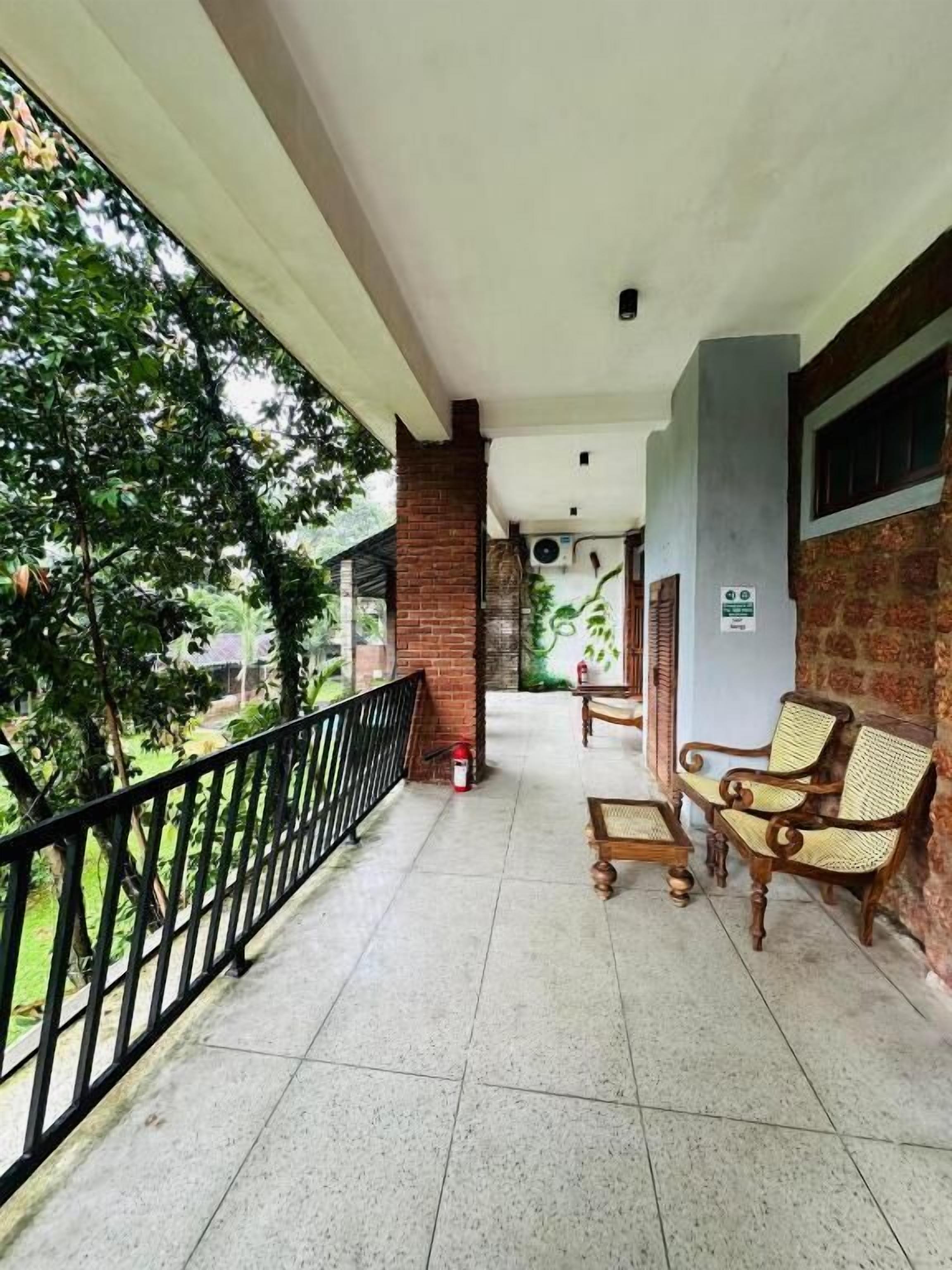 Un balcon abrité avec un sol carrelé, un pilier en briques et deux fauteuils en osier.