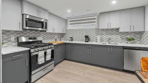 Una cocina moderna con gabinetes grises, un microondas de acero inoxidable, una estufa a gas y un lavavajillas.