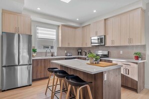 A modern kitchen with a central island, stainless steel appliances, and wooden cabinetry.