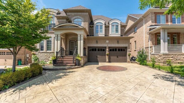 A large, two-story house with a stone facade, multiple garage doors, and a spacious driveway. - Spacious 7BR Home with Private Yard & Fast WiFi! (Brampton)