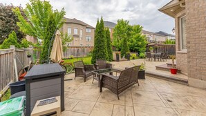 An outdoor patio with wicker furniture, a barbecue grill, and potted plants. - Spacious 4BR Home with Private Yard & Fast WiFi (Brampton)