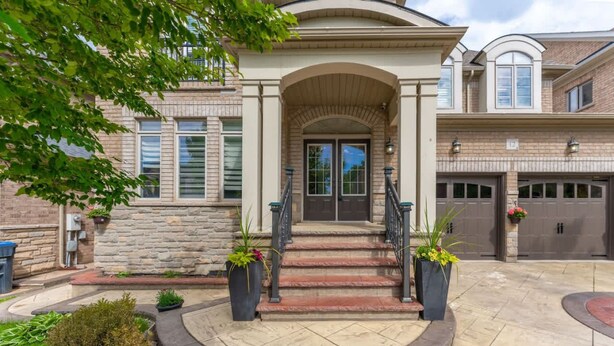 A two-story house with a stone facade, a front entrance with a staircase, and a garage with two doors. - Spacious 4BR Home with Private Yard & Fast WiFi (Brampton)