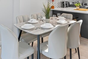 A dining area with a marble table set for six, surrounded by six chairs.