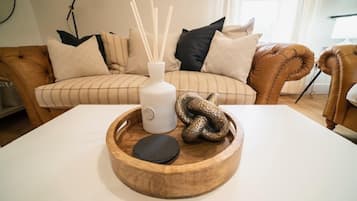 En stue med en brun lædersofa, et hvidt bord og en træbakke med en slange og et stearinlys.