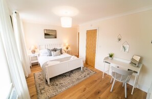 A bedroom with a bed, bedside tables, a desk, and a chair. - Foundry Farm Cottage (Hexham)