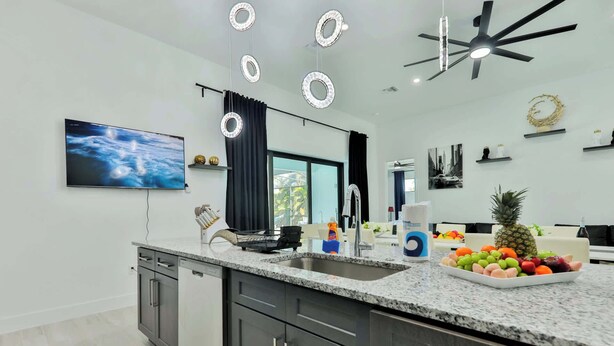 A modern kitchen with granite countertops, a built-in dishwasher, and a large window.