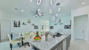 A modern kitchen with a granite countertop, a central island, and a ceiling fan.