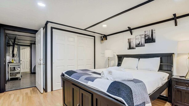 Un dormitorio con cama, mesitas de noche, lámpara y puerta que da a otra habitación.