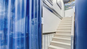 Una escalera con barandilla blanca y un muro perforado al fondo.