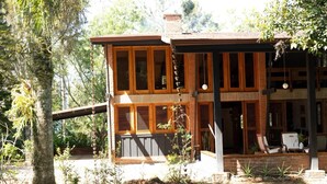 Ein zweistöckiges Haus mit überdachter Veranda, Holzläden und einer Ziegelstein-Fassade.