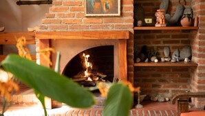 Ein Kamin aus Backsteinen mit Feuer, umgeben von Regalen mit Keramik und Figuren.