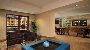 Un vestíbulo de hotel con una zona de estar, una mesa de billar y un comedor con televisor.