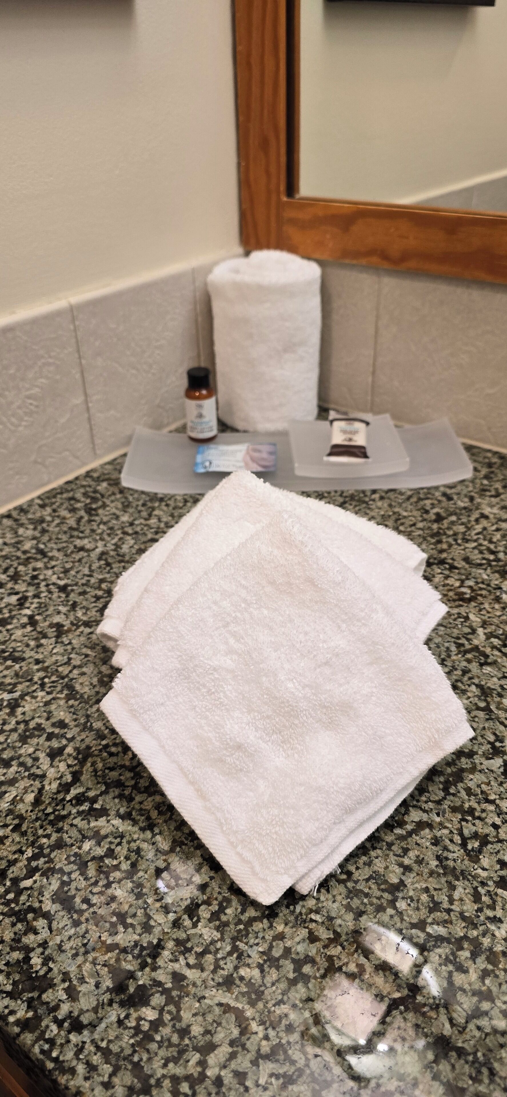 A bathroom counter with a white towel, a bottle of hand soap, and a bar of soap.