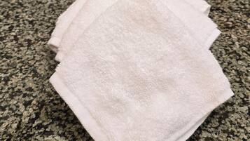 A bathroom counter with a white towel, a bottle of hand soap, and a bar of soap.