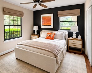 A bedroom with a bed, two bedside tables, a ceiling fan, and two windows with blinds.