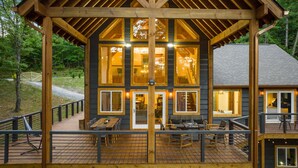 A wooden cabin with multiple windows, a deck, and a covered patio area. - Spacious 5-bedroom house/ Game Room/Pool Table/Firepit/HotTub/Generator (Blue Ridge)