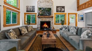 A living room with a fireplace, two sofas, a coffee table, and a TV. - Spacious 5-bedroom house/ Game Room/Pool Table/Firepit/HotTub/Generator (Blue Ridge)
