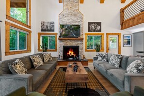 A living room with a fireplace, two sofas, a coffee table, and a TV. - Spacious 5-bedroom house/ Game Room/Pool Table/Firepit/HotTub/Generator (Blue Ridge)