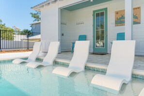 A pool area with white lounge chairs and a door leading to a covered porch. - Glimmer! Sleeps 26! 2 Blocks From The Beach! (Destin)