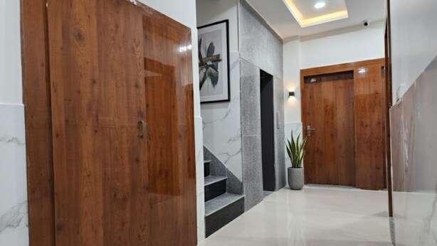 A hallway with wooden doors, a marble staircase, and a potted plant. - Hotel The Orchid Plaza (Samba)