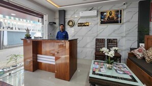 A reception area with a marble wall, a reception desk, a ceiling fan, and a framed picture on the wall. - Hotel The Orchid Plaza (Samba)