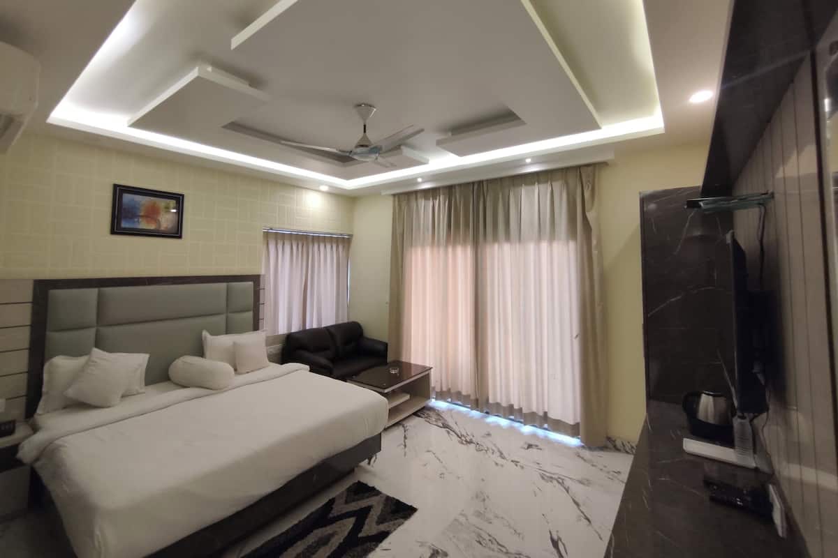 A modern bedroom with a bed, a sofa, a ceiling fan, and a shower area.