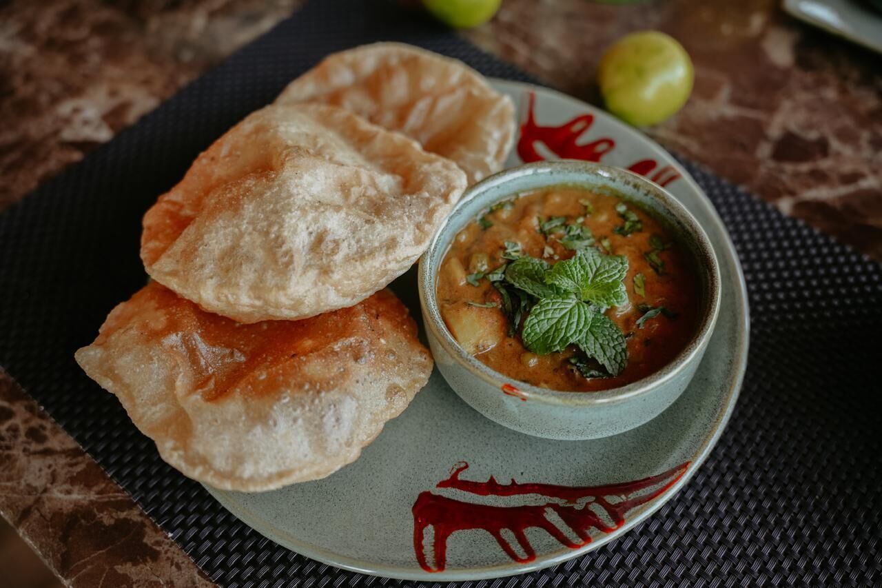 A plate with two pieces of fried bread and a bowl of soup garnished with mint leaves.