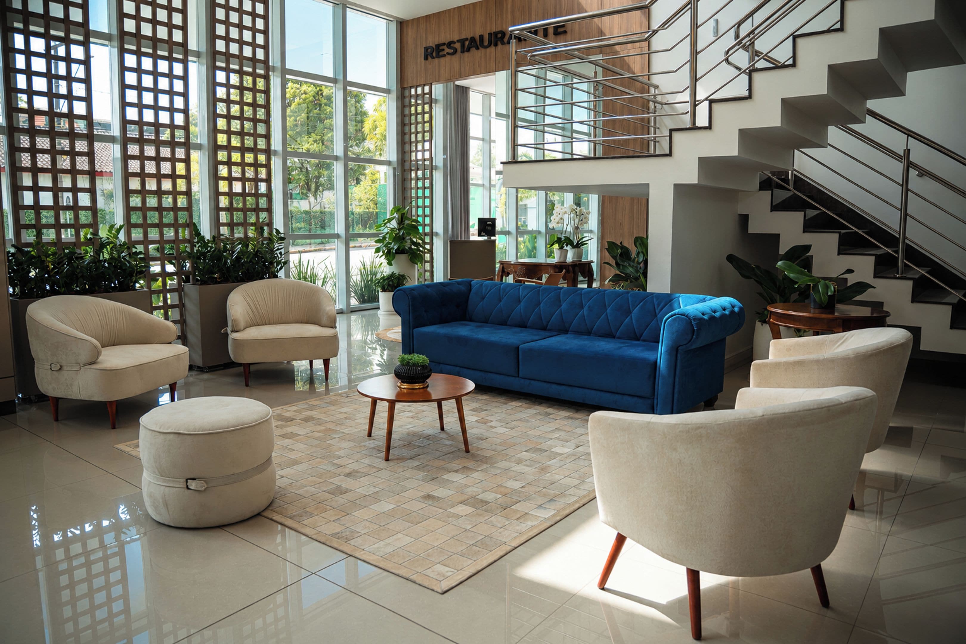 Un espacio habitable amplio con un sofá azul, sillones color beige y una mesa de centro.