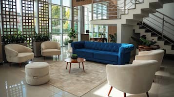 Un espacio habitable amplio con un sofá azul, sillones color beige y una mesa de centro.