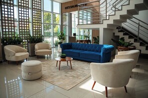 A spacious living area with a blue sofa, beige armchairs, and a coffee table. - Hotel Gran Santa Catarina (Indaial)