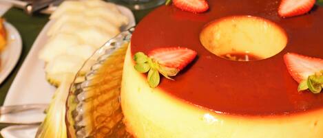 Una mesa de postres con flan, frutero y cafeteras.
