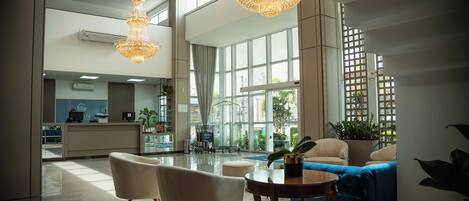 A spacious lobby with a reception desk, seating area, and large windows allowing natural light.