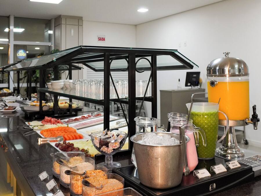 Un bufé con diferentes opciones de comida y un dispensador de jugo.