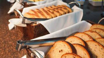 A buffet with various food items, including bread and pastries, arranged on tables with serving utensils.