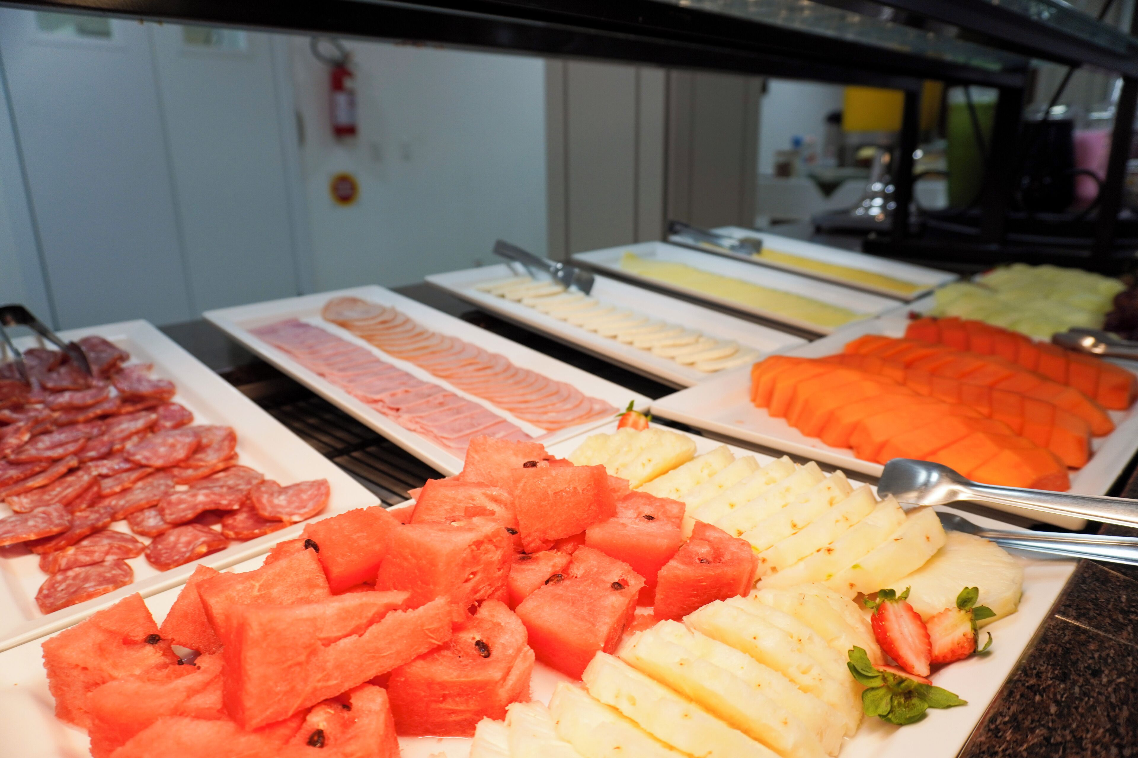 A buffet with various food items including sliced meats, fruits, and vegetables.