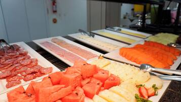 A buffet with various food items including sliced meats, fruits, and vegetables.