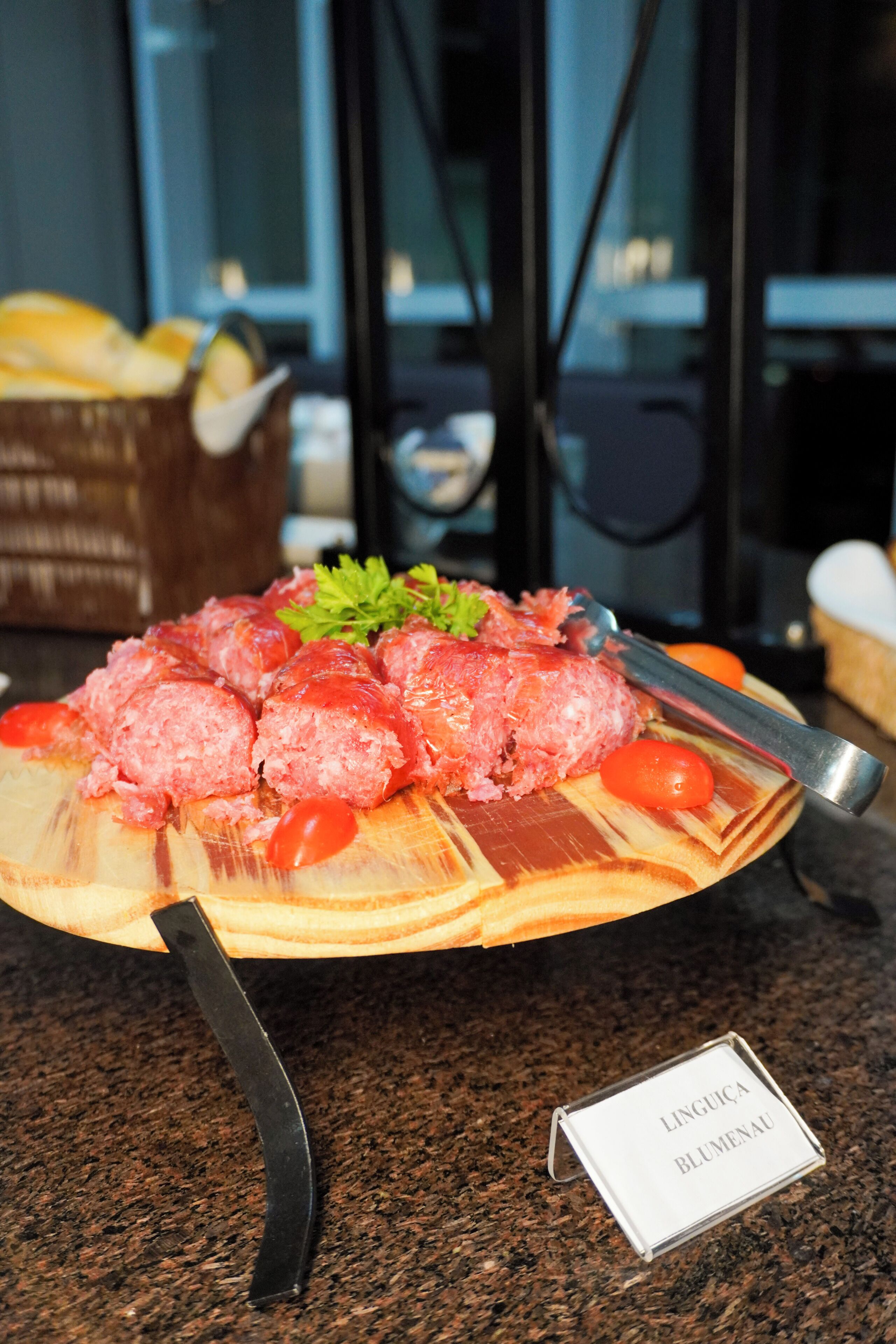 A wooden board with a dish of food, a knife, and a name tag.