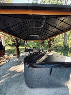 A covered outdoor seating area with a concrete table, a wooden bench, and a metal roof structure. - 6 acre private nature retreat glamping cabin. (Fort Plain)