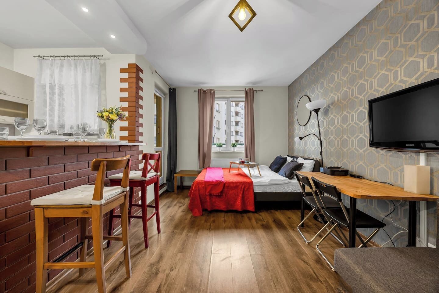 A compact hotel room with a bed, a desk, a chair, a TV, and a window.
