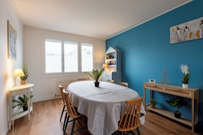 Un espace repas comprenant une table ronde, des chaises, un buffet et des plantes en pot.