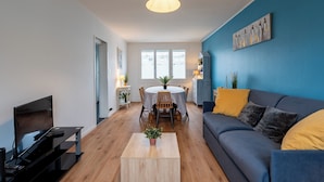 Un salon moderne comprenant un téléviseur, un canapé, une table basse et un coin repas.
