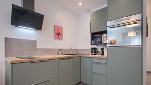 Una cocina moderna con un televisor de pantalla plana sobre la encimera, un microondas y un horno empotrado.