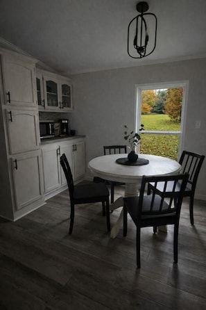 A kitchen with white cabinets, a round dining table, and chairs. - Fox Lake Escape- Peaceful Cabin for Outdoor Enthusiasts (Tracy)