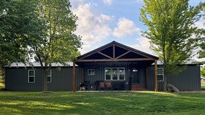 Een gebouw met een overdekte patio, een barbecue en een zithoek.