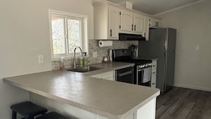 Een keuken met een centraal eiland, barkrukken, een koelkast en een fornuis.
