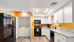 A modern kitchen with white cabinets, a black refrigerator, a microwave, and an oven. - Relaxing 4BR with Pool, Game Room & BBQ Fun (Tucson)