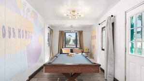 A pool table in a hallway with a view to the outside, a ceiling light, and a door with curtains. - Relaxing 4BR with Pool, Game Room & BBQ Fun (Tucson)