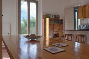 Una cucina con un tavolo di legno, due sgabelli, una ciotola di biscotti e un armadietto con ante in vetro.